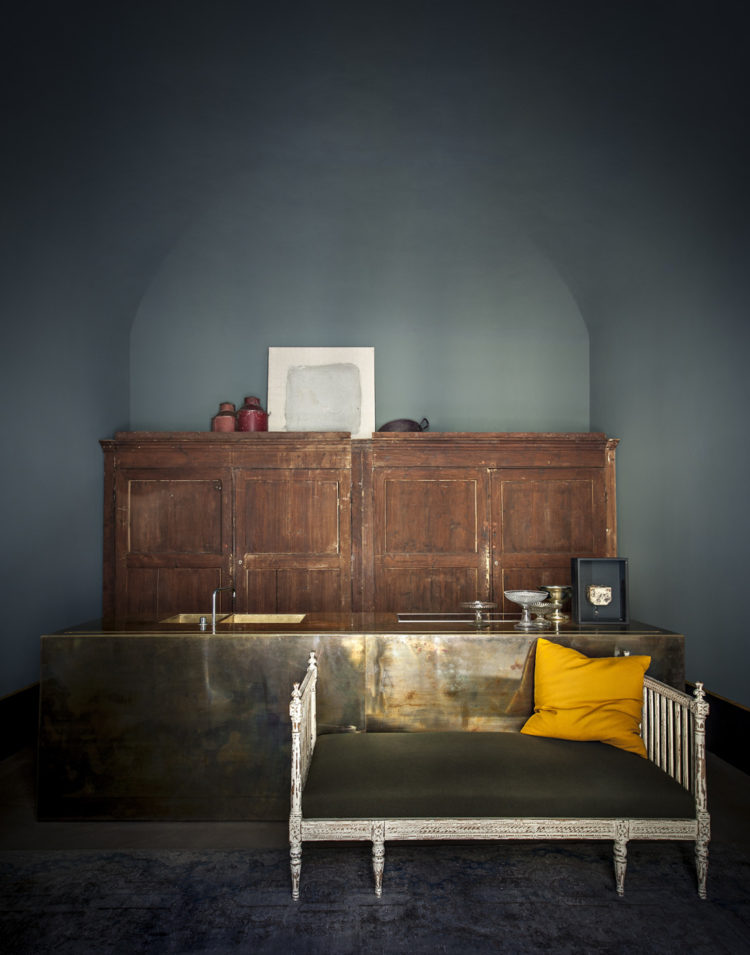dark walls and a gold cushion by dimore studio