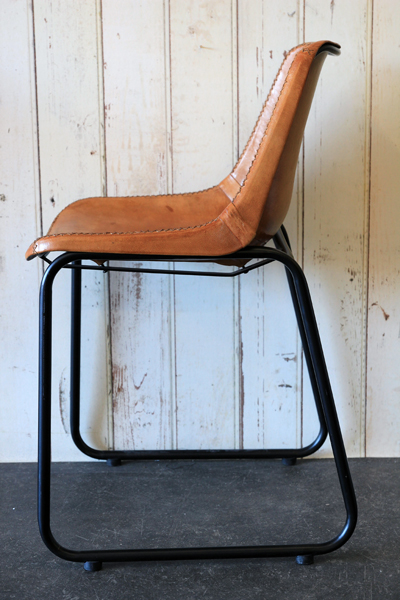 the industrial style dining chair is made from tan leather with copper colour rivets 