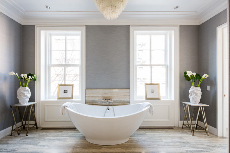 freestanding bathtub with grey walls and wooden floor
