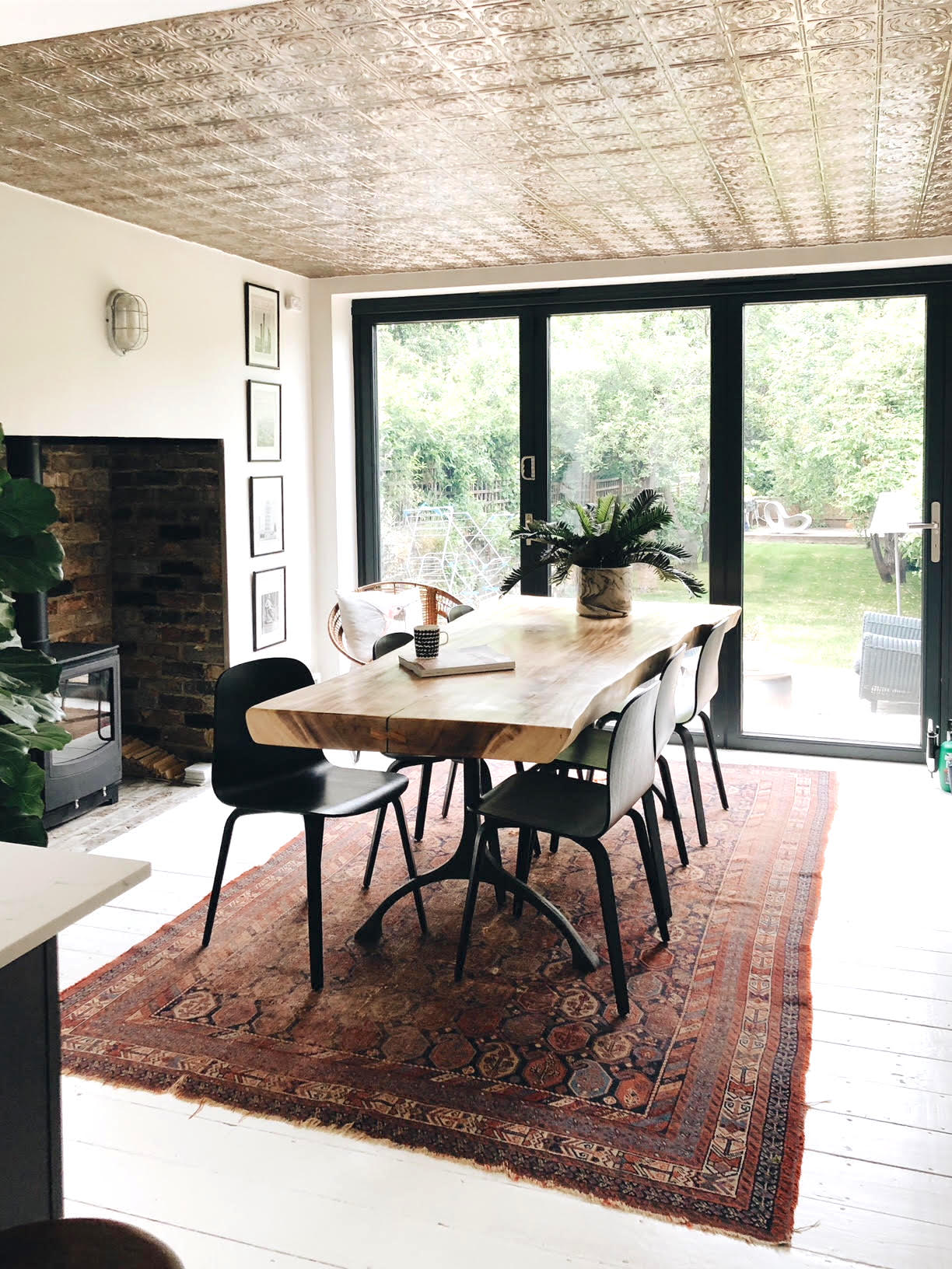 Kate Watson-Smyth looks at using the ceiling as a fifth wall. In her dining room which forms the extension she covered the ceiling with silver tin tiles. With a ceiling too low for a pendant the silver reflects the light from outside the black bi-fold doors. #madaboutthehouse #fifthwall #diningroom