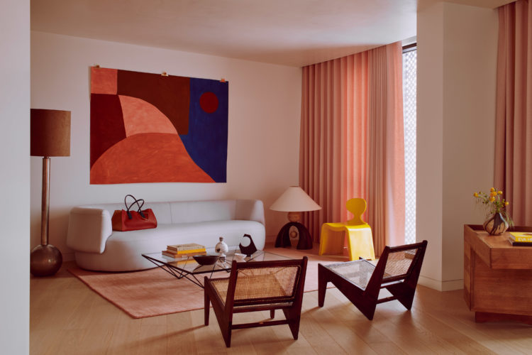 The living room; artwork by Caroline Devernaud hung above the FOA Sofa by Christophe Delcourt for Collection Particulière with a Roksanda bag on top of it. Nickel floor lamp with spherical base; François Châtain floor lamp. CREDIT: PHOTOGRAPHY BY MICHAEL SINCLAIR, STYLING BY OLIVIA GREGORY