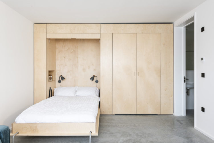 the owners have created a wall of cupboards that houses a bed as well (image via the modern house)
