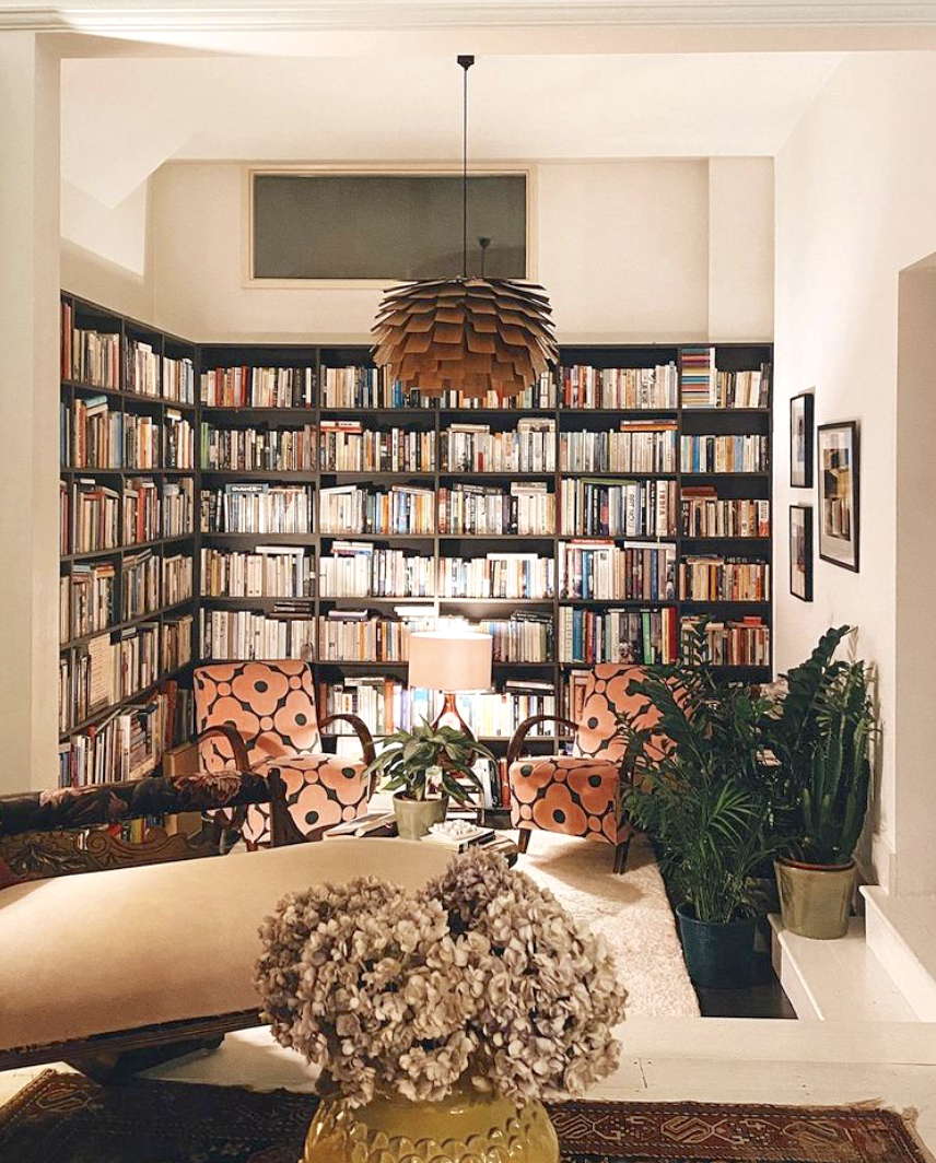 Kate Watson-Smyth's library with reading chairs in Velvet Spot Flower Jade by Orla Kiely, cream chaise, large mid-century pendant light and yellow vase with dried hydrangeas