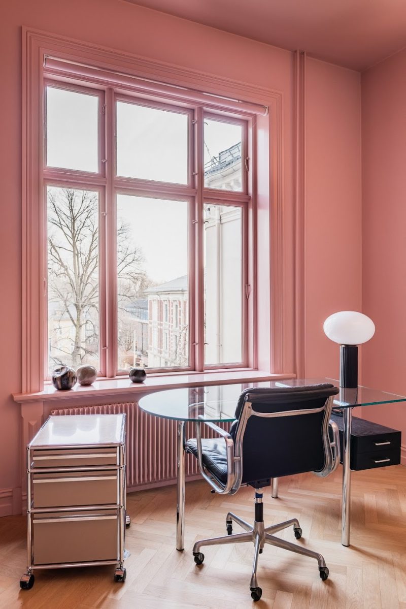 Home office with pink walls, large windows, USM glass and steel desk, black leather swivel desk chair in the apartment belonging to Einar Jone Rønning Mateusz Michalowski and stylist: Josefine Johansson Studio
