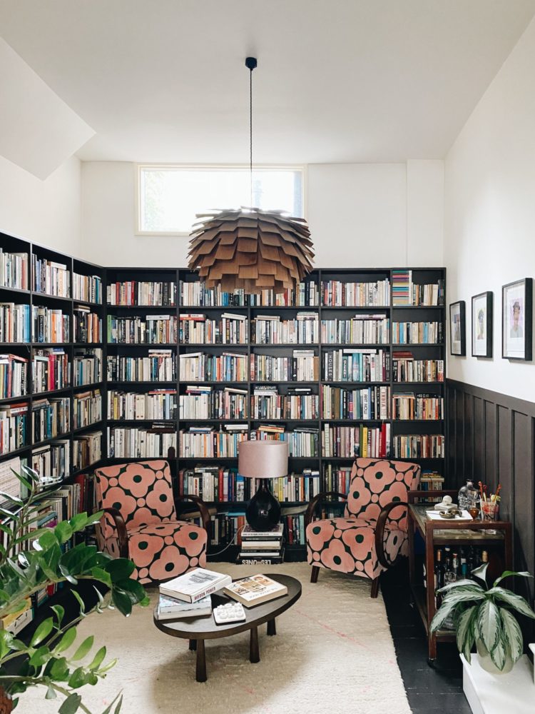 library at the home madaboutthehouse.com. half wall panelling in chocolate brown, 2 orla kiely upholstered mid-century modern armchairs small oval dark wood coffee table and cream rug
