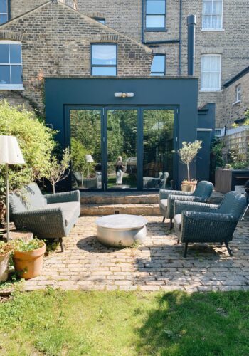 Victorian terrace house black extension, outdoor sofa, armchairs, coffee table and floor lamp, garden at madaboutthehouse.com